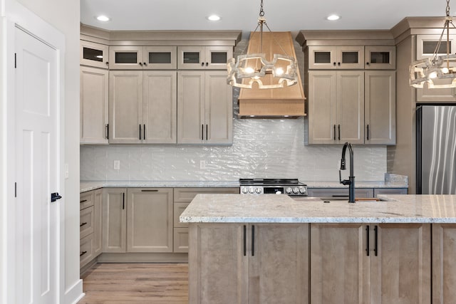 kitchen featuring pendant lighting, light stone counters, light wood-type flooring, and appliances with stainless steel finishes