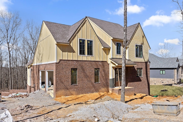 view of front of house with board and batten siding, brick siding, and roof with shingles