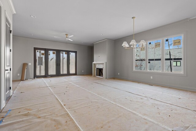 unfurnished living room with a fireplace, baseboards, and a notable chandelier