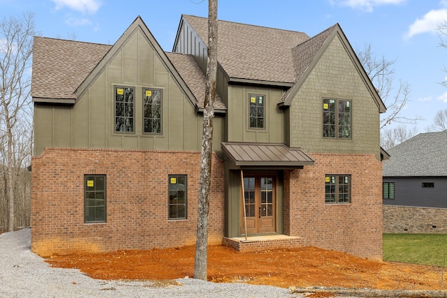 view of front of property featuring brick siding, french doors, board and batten siding, and a shingled roof