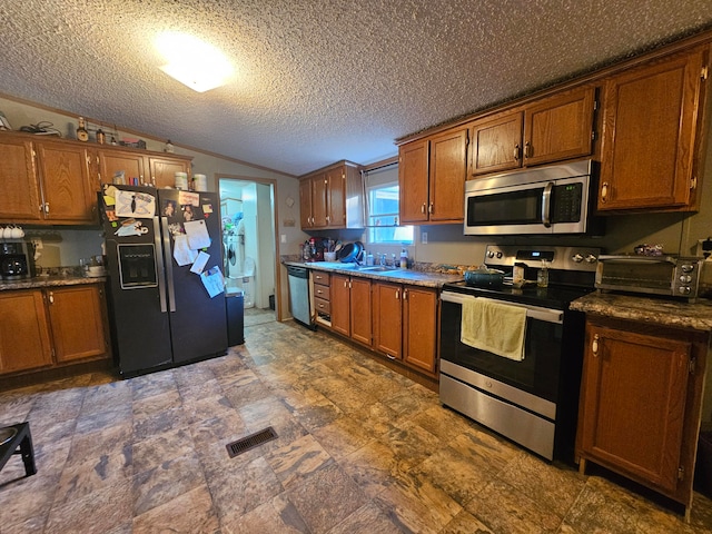 kitchen featuring lofted ceiling, a textured ceiling, appliances with stainless steel finishes, and sink