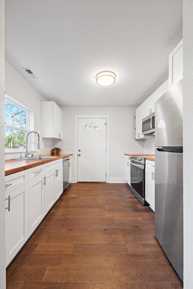 kitchen with white cabinets, appliances with stainless steel finishes, sink, and wooden counters