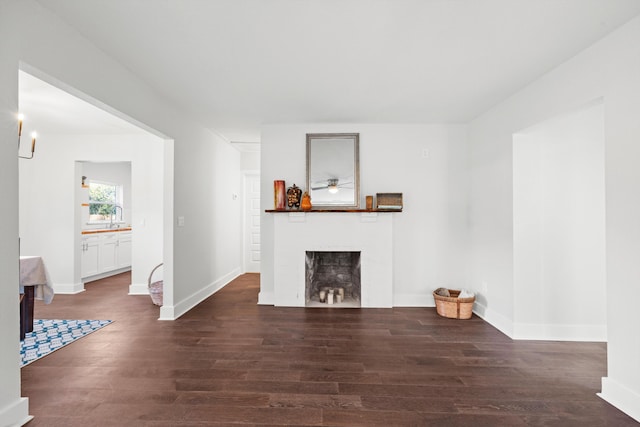 unfurnished living room with dark hardwood / wood-style floors, sink, and a fireplace