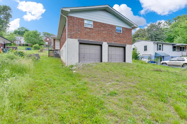 view of home's exterior featuring brick siding, a garage, cooling unit, a yard, and driveway