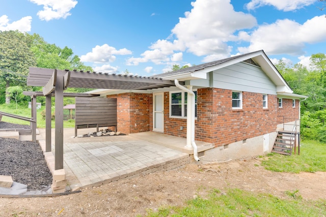 rear view of house featuring a pergola, a patio area, and brick siding