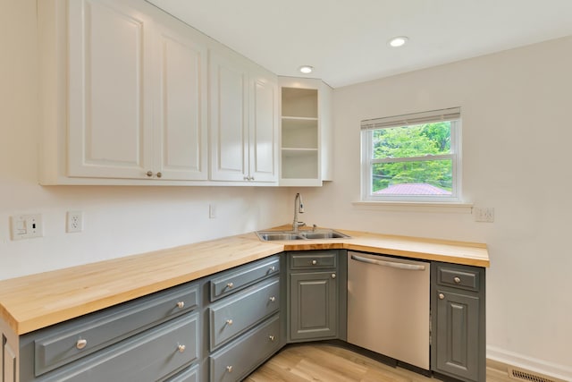 kitchen featuring gray cabinetry, wooden counters, a sink, and dishwasher