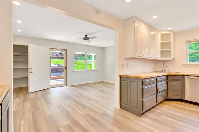 kitchen featuring light wood-style floors, baseboards, stainless steel dishwasher, and a sink