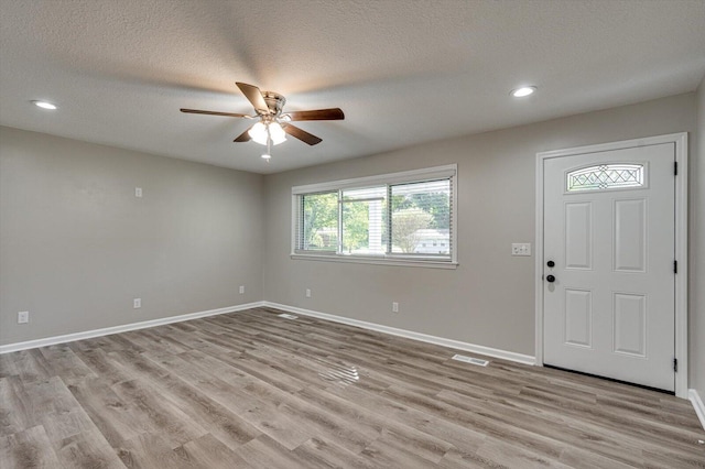 foyer entrance with ceiling fan, a textured ceiling, and light hardwood / wood-style flooring