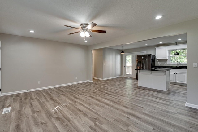 kitchen featuring pendant lighting, light wood-type flooring, plenty of natural light, and white cabinetry