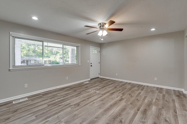 empty room featuring ceiling fan, a textured ceiling, and light wood-type flooring