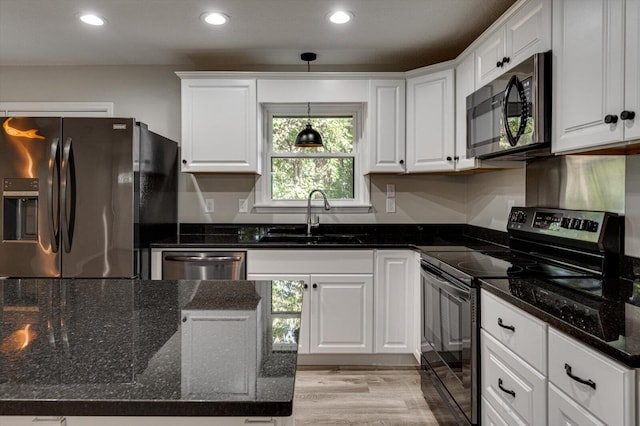 kitchen featuring dark stone countertops, stainless steel appliances, sink, and white cabinetry