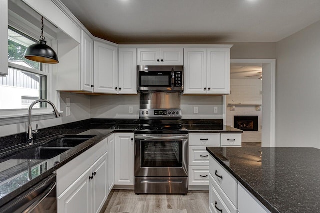 kitchen with white cabinets, appliances with stainless steel finishes, sink, and dark stone counters