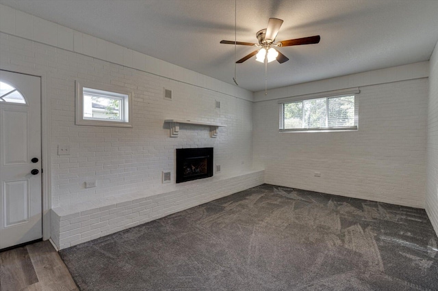 unfurnished living room with ceiling fan, a fireplace, dark hardwood / wood-style floors, and a wealth of natural light