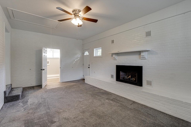 unfurnished living room with ceiling fan, carpet floors, and brick wall