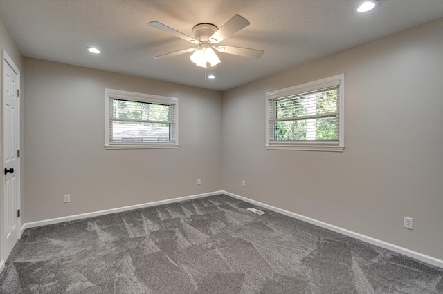 unfurnished room with ceiling fan, plenty of natural light, dark carpet, and a textured ceiling