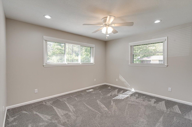 empty room with ceiling fan, a textured ceiling, and dark colored carpet