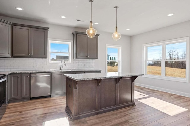 kitchen with plenty of natural light, a sink, appliances with stainless steel finishes, and a breakfast bar