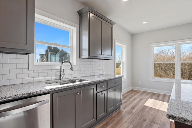 kitchen featuring a sink, light wood finished floors, dishwasher, recessed lighting, and decorative backsplash