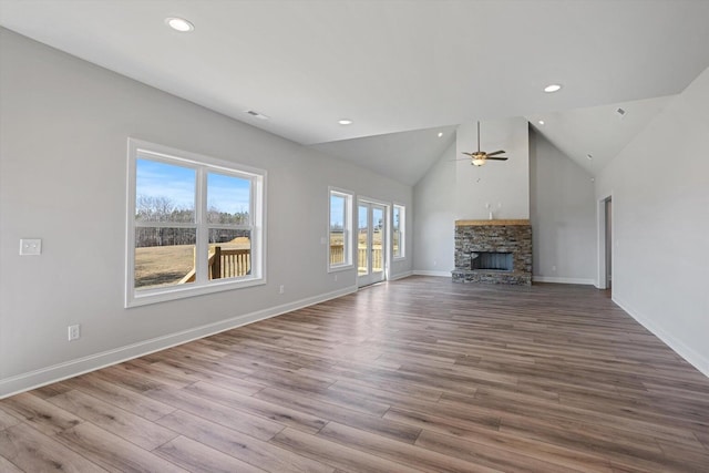 unfurnished living room featuring ceiling fan, a stone fireplace, wood finished floors, baseboards, and recessed lighting