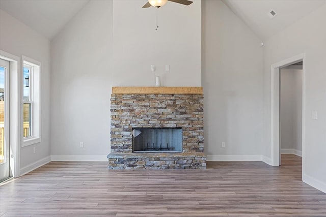 unfurnished living room featuring light hardwood / wood-style floors, a stone fireplace, and plenty of natural light