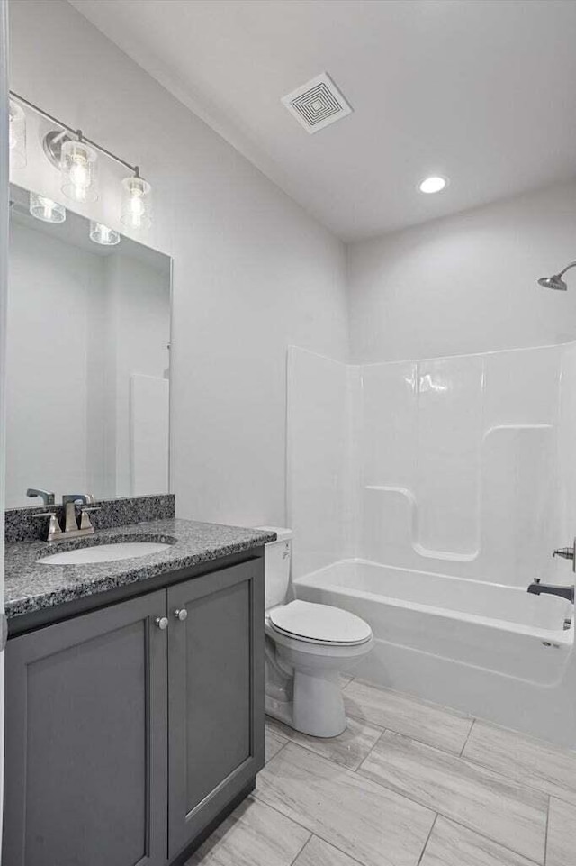 bathroom featuring visible vents, vanity, marble finish floor, toilet, and shower / washtub combination