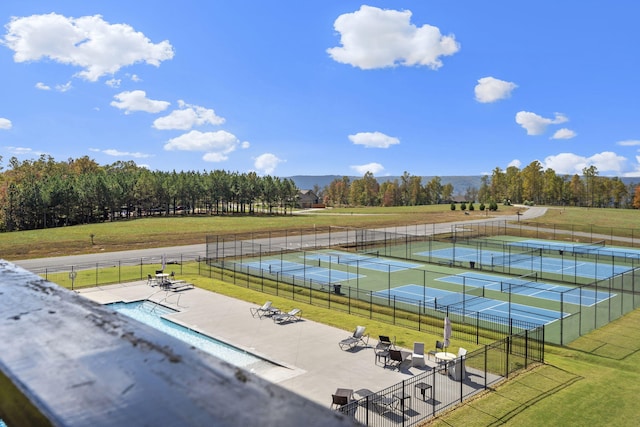 exterior space featuring a lawn, fence, and a tennis court