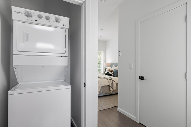 washroom with dark hardwood / wood-style floors and stacked washer and dryer