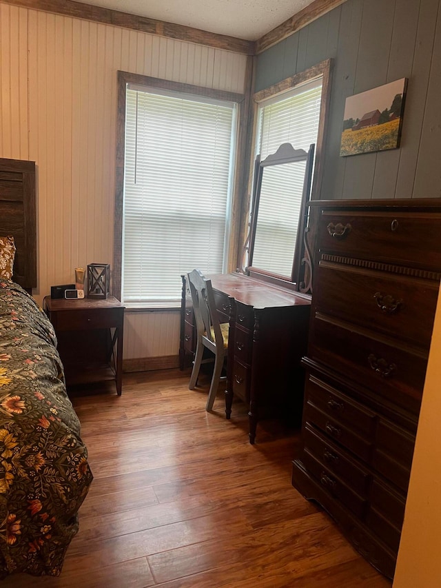 bedroom with wood walls and wood-type flooring