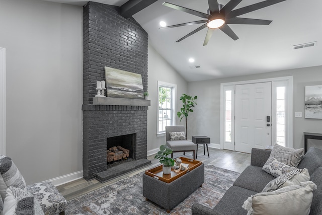 living room featuring lofted ceiling with beams, a brick fireplace, ceiling fan, and wood-type flooring