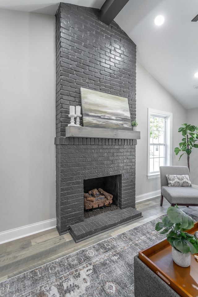 living room featuring a brick fireplace, lofted ceiling with beams, and hardwood / wood-style floors