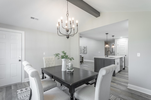 dining space with lofted ceiling with beams, a chandelier, sink, and dark hardwood / wood-style floors