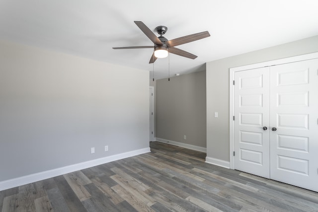 unfurnished bedroom with ceiling fan, a closet, and dark hardwood / wood-style flooring