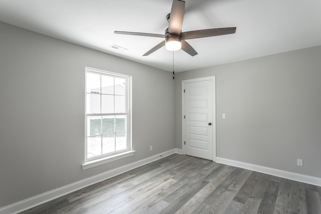 spare room with a healthy amount of sunlight, ceiling fan, and dark wood-type flooring