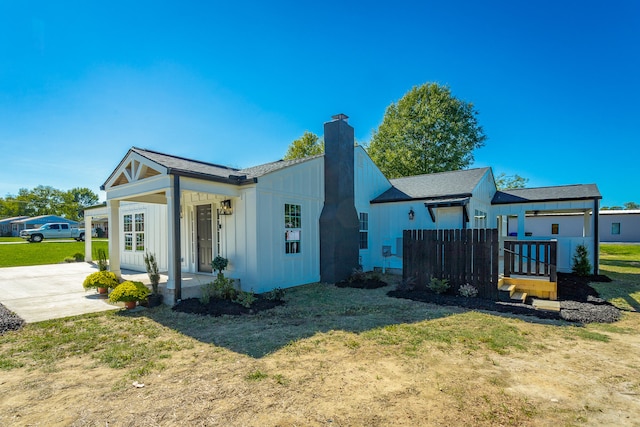 view of side of property featuring a lawn and covered porch