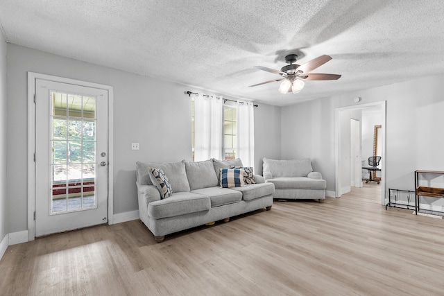 living room with ceiling fan, light hardwood / wood-style floors, and a textured ceiling