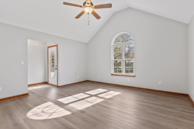 spare room with ceiling fan, vaulted ceiling, and light wood-type flooring