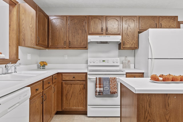 kitchen featuring a textured ceiling, white appliances, and sink