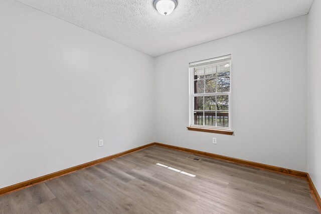 unfurnished room featuring wood-type flooring and a textured ceiling