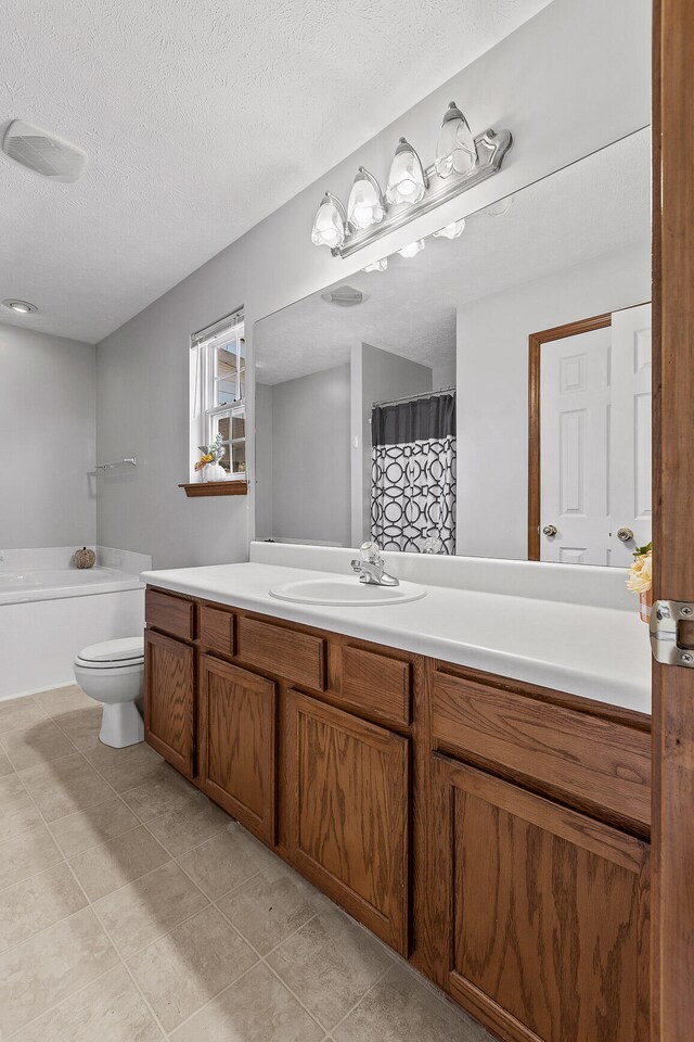 bathroom with tile patterned floors, vanity, toilet, and a textured ceiling