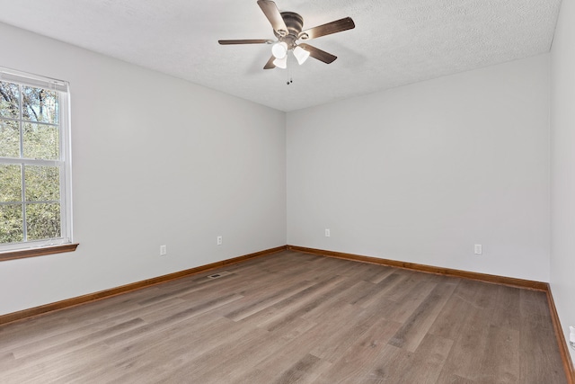 empty room with ceiling fan, light hardwood / wood-style floors, and a textured ceiling