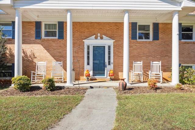 doorway to property featuring covered porch and a yard