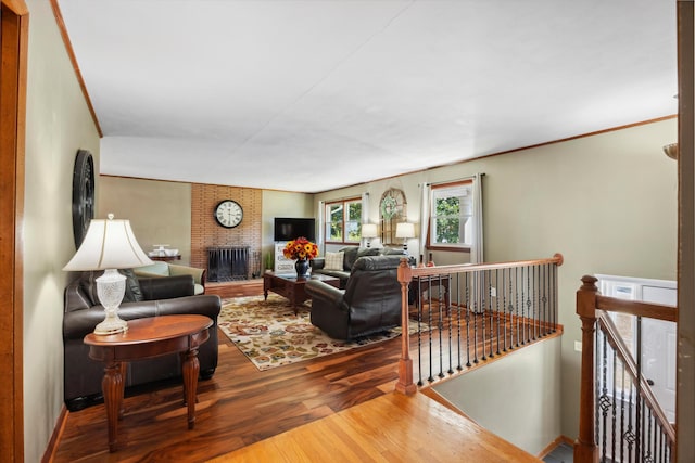 living room featuring crown molding, a brick fireplace, and hardwood / wood-style flooring