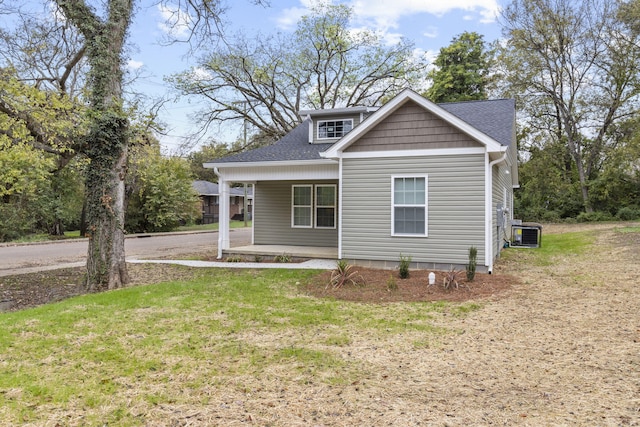 view of front facade featuring cooling unit, covered porch, and a front yard