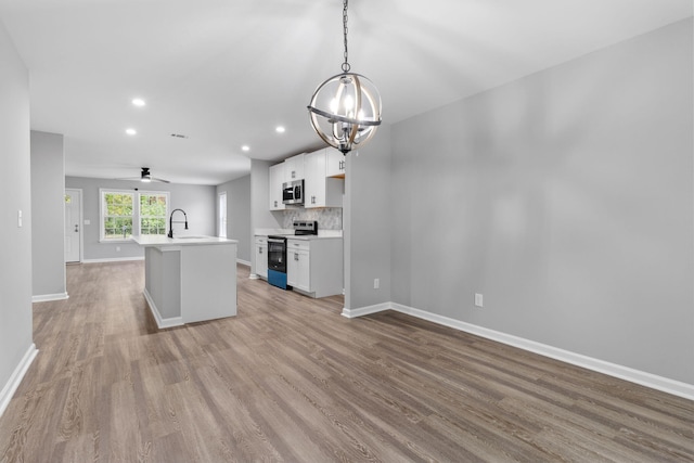 kitchen featuring stainless steel appliances, a kitchen island with sink, decorative light fixtures, light hardwood / wood-style floors, and white cabinetry