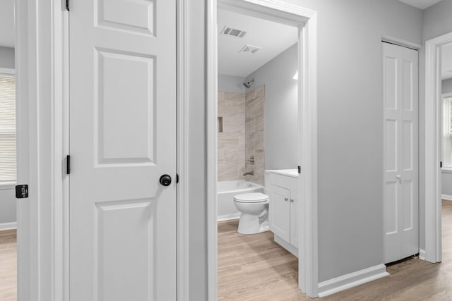 full bathroom with vanity, hardwood / wood-style floors, tiled shower / bath combo, and toilet