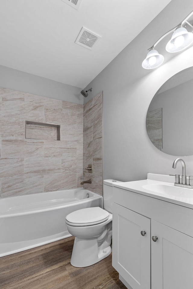 full bathroom with wood-type flooring, vanity, toilet, and tiled shower / bath combo