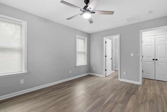 unfurnished bedroom featuring ceiling fan, a closet, and dark wood-type flooring