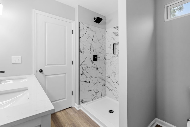 bathroom with hardwood / wood-style flooring, vanity, and a tile shower