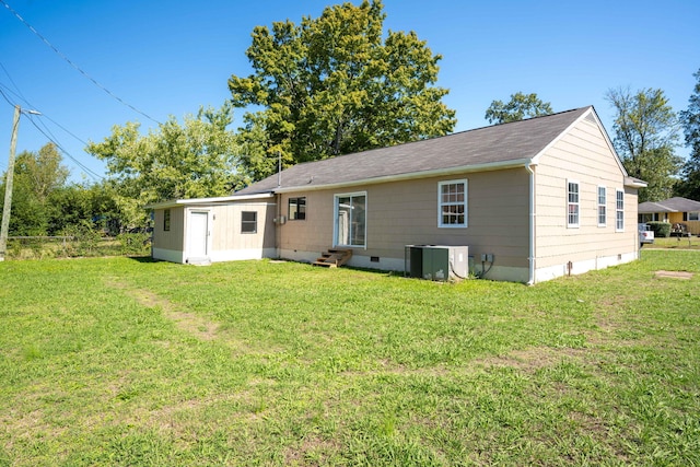 rear view of property featuring central AC unit and a lawn