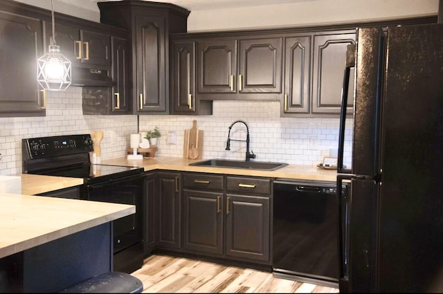 kitchen with black appliances, decorative light fixtures, sink, backsplash, and light hardwood / wood-style flooring